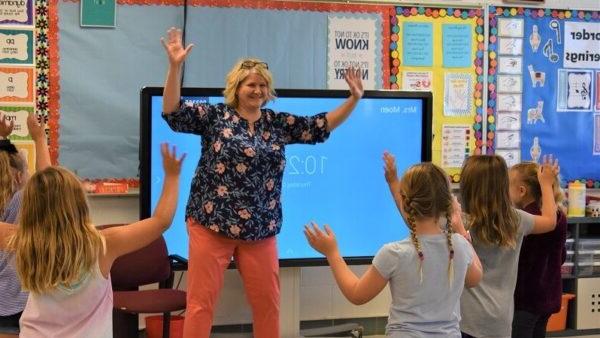 music teacher 和 students holding their arms up while moving to the beat of a song